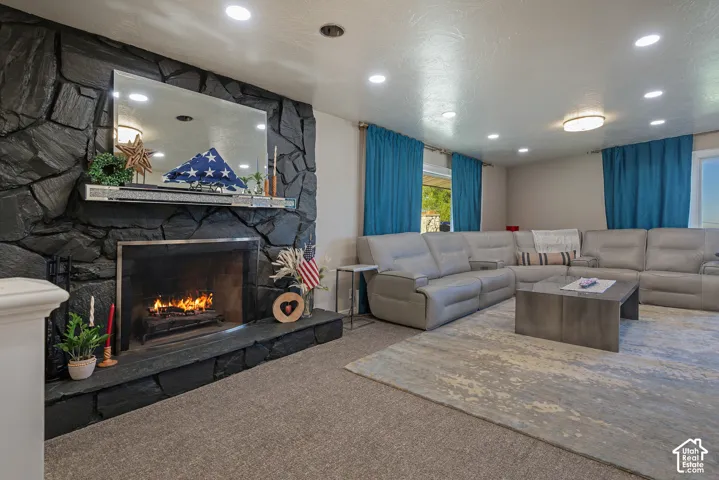 Full-height dark stone fireplace wall featuring a built-in metal mantel and integrated firebox with a stone hearth, complemented by recessed ceiling lighting
