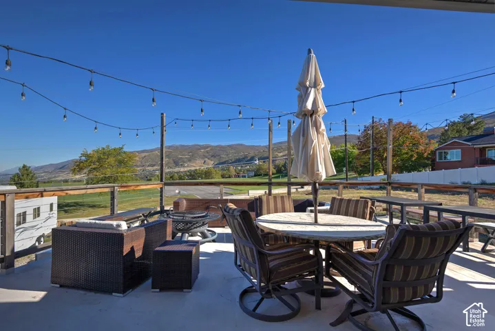 Elevated concrete patio featuring a cable-rail fence, string lighting, and mountain scenery