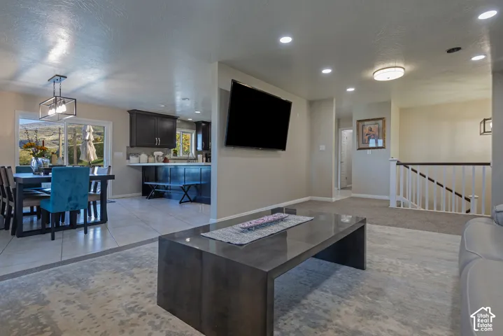 Open-concept main level featuring dark cabinetry, ceramic tile flooring, recessed lighting, and a white baluster staircase
