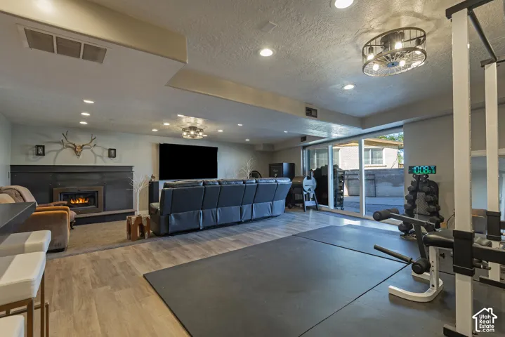 Recessed lighting, wood-finish flooring, built-in fireplace with a dark surround, and sliding glass doors
