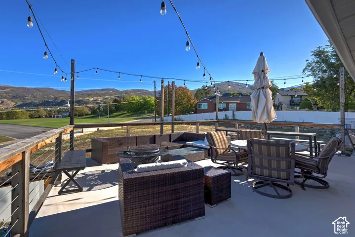 Elevated concrete patio featuring a wood-post railing with cable infill, string lighting, and mountain scenery