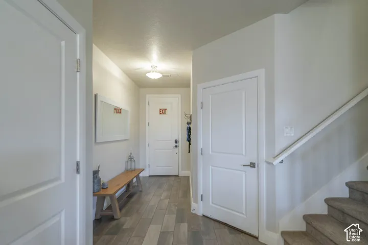 Entryway featuring wood-finish tile flooring, a painted solid-core door, carpeted stairs with a wall-mounted handrail, and a flush-mount ceiling light fixture