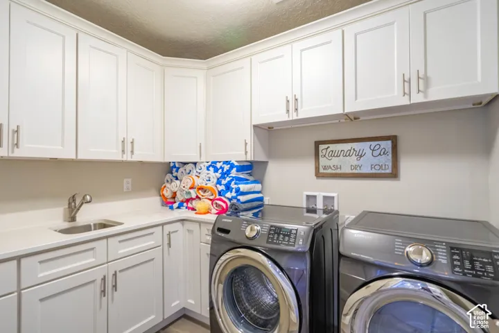 Laundry room featuring white shaker-style cabinetry, solid-surface countertops, an undermount stainless steel sink with a high-arch faucet, and brushed nickel hardware