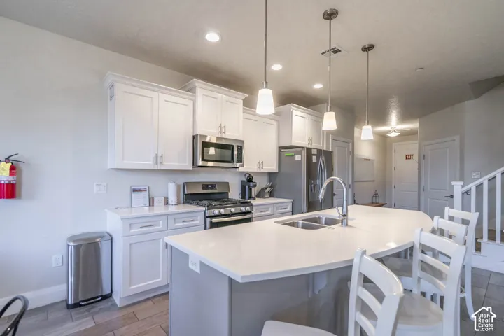 Kitchen featuring white cabinetry, center island with stone-surface countertop, stainless steel appliances, and pendant lighting
