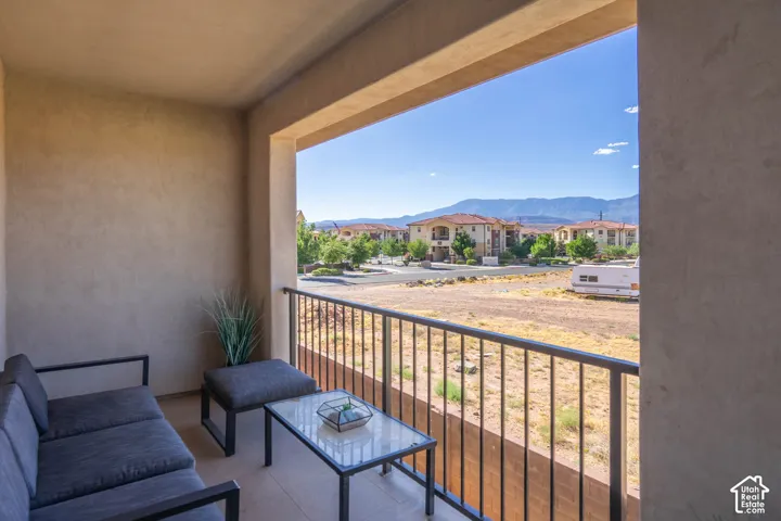 Covered balcony featuring a metal railing, stucco walls, and mountain scenery