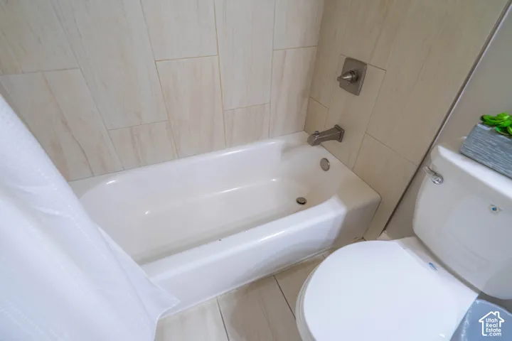 Bathtub with brushed nickel hardware, surrounded by vertically stacked light-toned wall tile