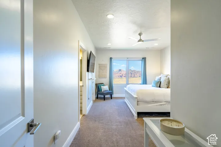 Interior space featuring neutral-toned carpeting, recessed lighting, a modern ceiling fan, and a window providing a backdrop of desert mountains