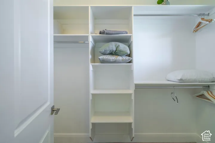 Walk-in closet featuring white built-in shelving, multiple tiered storage levels, and dual metal hanging rods