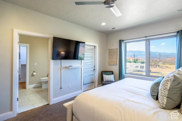 Large window with mountain backdrop, neutral wall color, ceiling fan, and access to exterior via a glass-panel door
