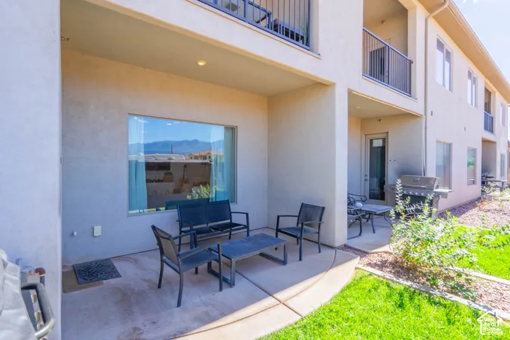 Covered concrete patio featuring a grass lawn, metal balcony railings, and mountain backdrop