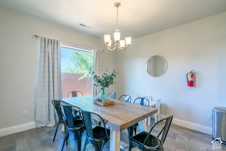 Large window with natural light, multi-light chandelier, and wood-finish tile flooring