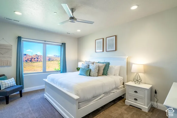 Neutral-toned room featuring a large picture window, recessed lighting, and a modern three-blade ceiling fan, set against a prominent red rock mountain backdrop
