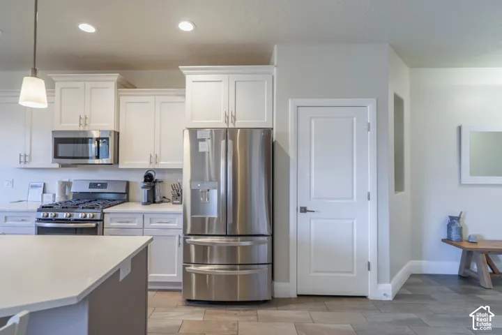 Kitchen featuring white shaker-style cabinetry, stainless steel appliances, a stone-finish countertop, and tile flooring