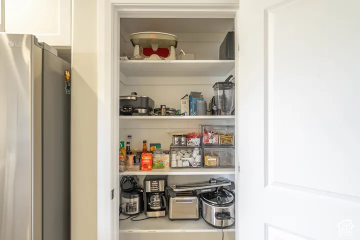 Built-in pantry featuring four levels of fixed shelving and a shaker-style panel door
