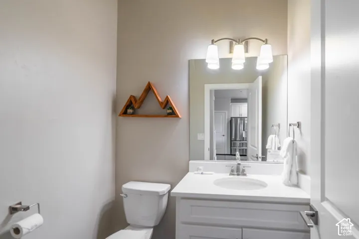 White vanity cabinet featuring a solid surface countertop with an integrated basin, three-light vanity fixture, and large rectangular mirror