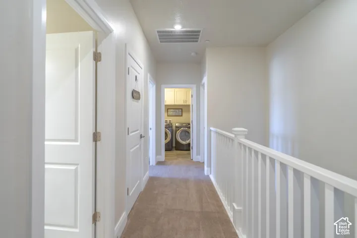 Hallway featuring neutral carpet, white paneled interior doors, and a white baluster railing