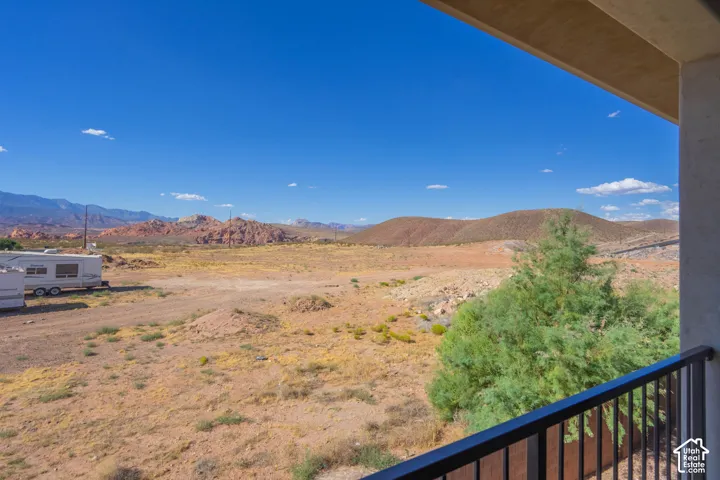 Covered balcony with black metal railing, offering expansive desert landscape and mountain terrain