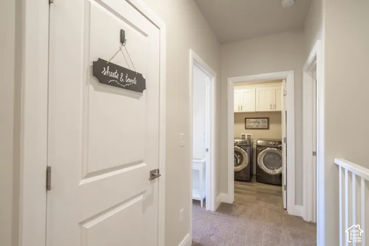 Hallway featuring solid-core doors, wall-to-wall carpeting, and wood-finish flooring in the laundry area with built-in overhead cabinetry