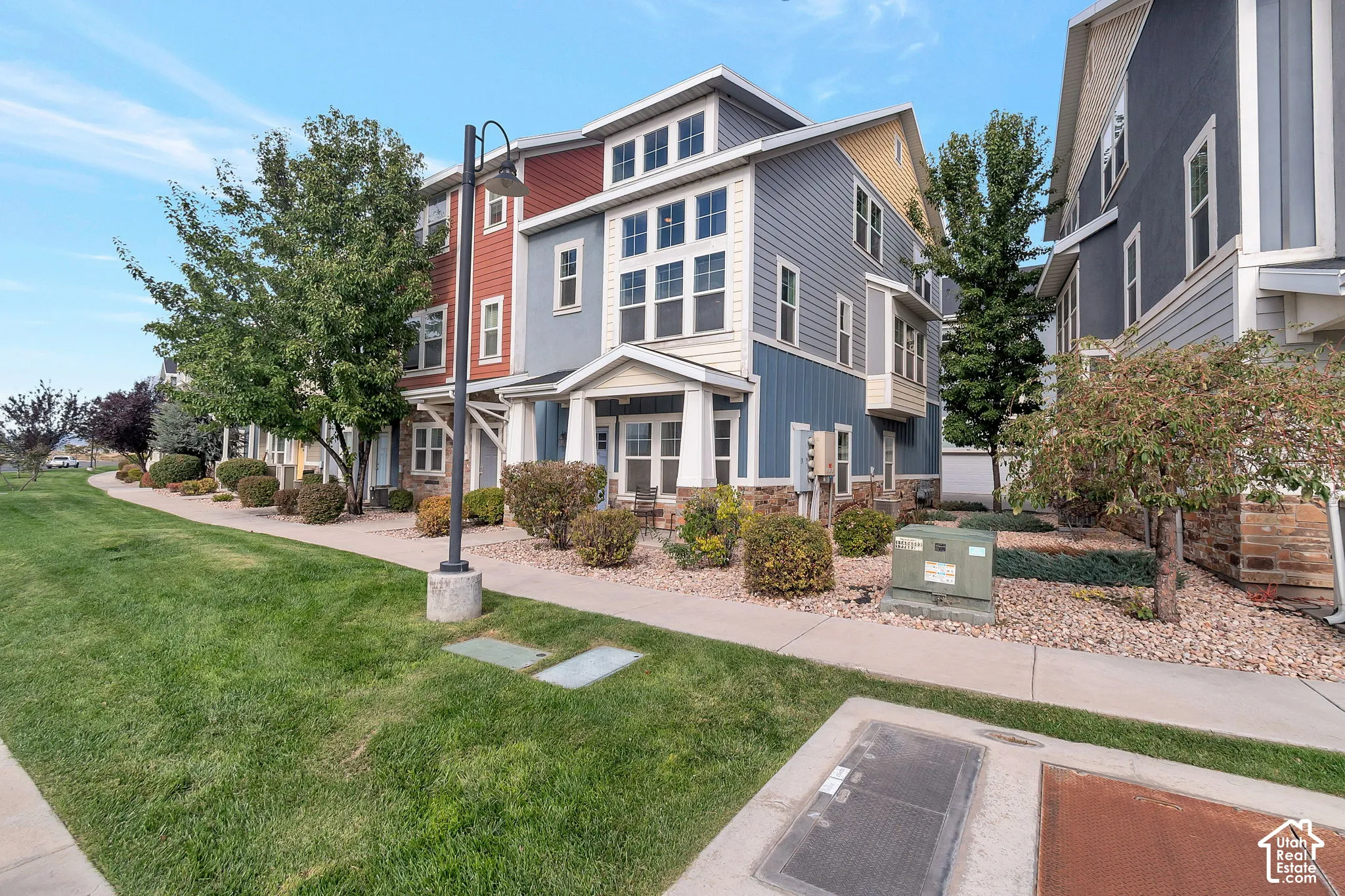 Multi-story exterior featuring composite siding, stone masonry accents, multi-pane windows, and a covered entryway with structural columns