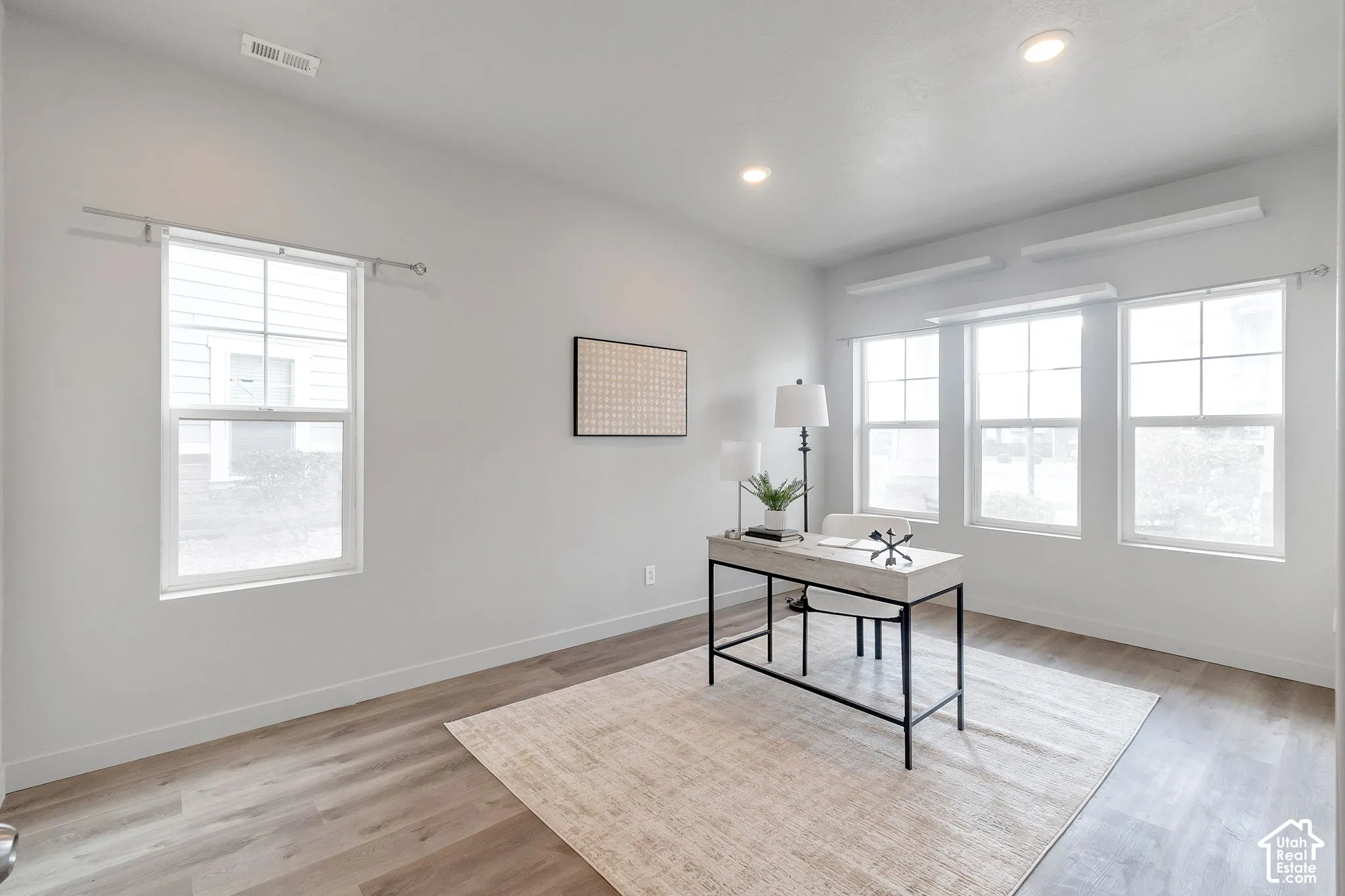Bright room featuring wood-finish flooring, recessed lighting, and multiple windows with muntin detailing