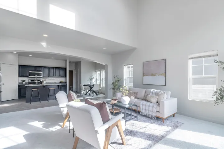 High-ceilinged interior featuring a kitchen with dark cabinetry, breakfast bar, recessed lighting, and large windows