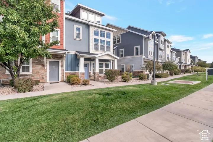 Multi-level exterior featuring a combination of stone veneer and siding, covered front entryways, multi-pane windows, and concrete walkways