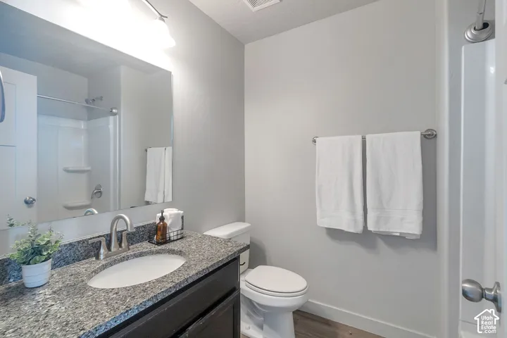 Bathroom featuring a vanity with a stone-finish countertop, undermount sink, brushed nickel hardware, and a tub-shower combination