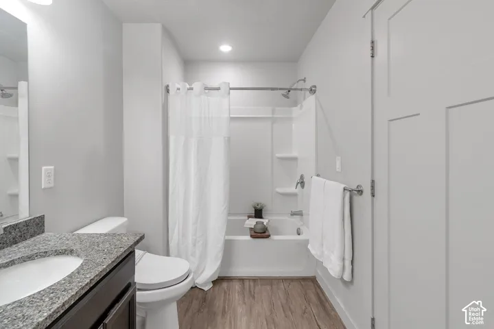 Bathroom featuring a dark wood-finish vanity, stone-patterned countertop with integrated sink, recessed lighting, and a tub-shower combination with built-in shelving