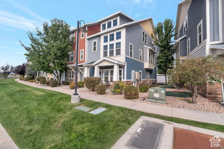 Multi-story exterior featuring composite siding, stone masonry accents, multi-pane windows, and a covered entryway with structural columns