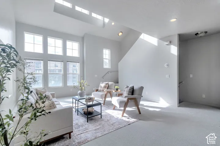 Vaulted ceilings featuring a large skylight, expansive multi-pane windows, recessed lighting, and a metal handrail