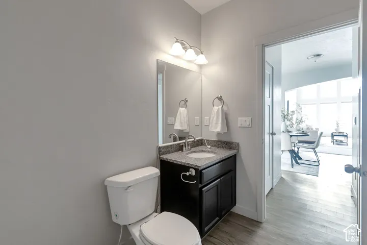 Dark wood cabinetry, stone-finish countertop with an integrated basin, wall-mounted three-light fixture, and polished metal hardware