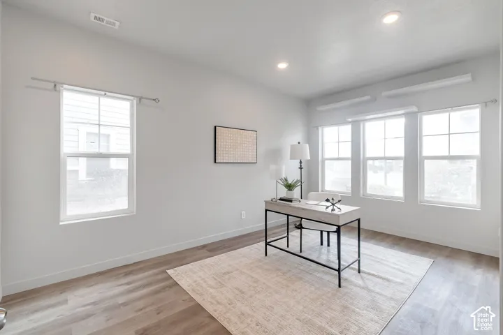 Bright room featuring wood-finish flooring, recessed lighting, and multiple windows with muntin detailing