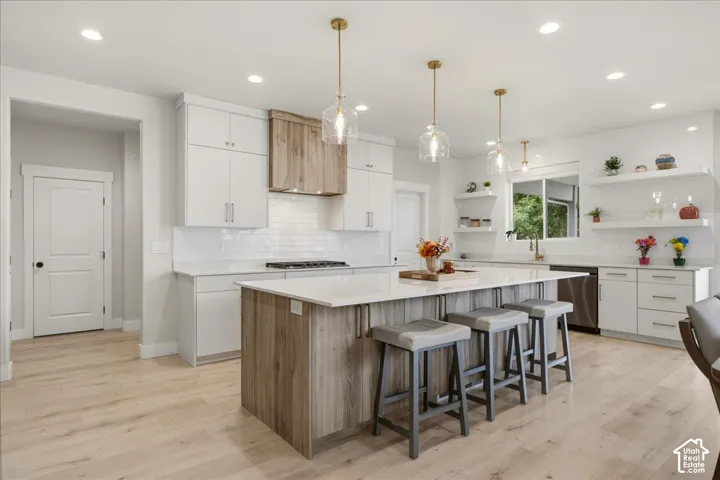 Gourmet kitchen with floor-to-ceiling European-style cabinetry, upgraded quartz countertops, ceiling-height tile backsplash, 5 burner gas range, double ovens, black stainless steel appliances, & soft-close cabinetry