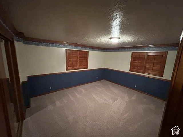 Downstairs Bedroom one featuring carpeting, wood-trimmed windows with integrated shutters, chair rail molding, and crown molding