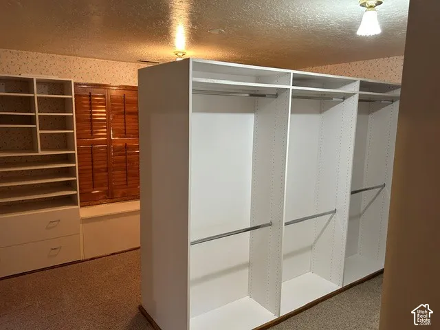 Upstairs closet converted from fourth bedroom. Custom white built-in cabinetry featuring tiered shelving, integrated drawers, and metal hanging rods, complemented by wooden window shutters