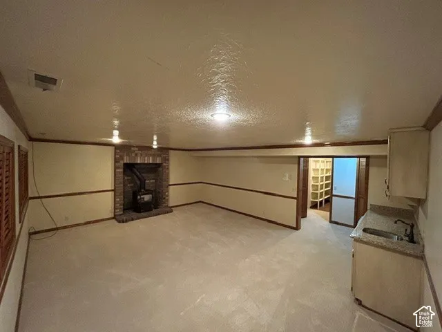 Downstairs Family Room with Kitchen featuring a brick-surround wood-burning stove, built-in cabinetry with stone-surfaced countertop, integrated sink, and recessed ceiling lighting