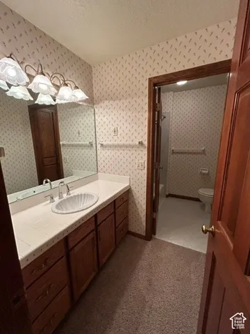 Upstairs Full Bathroom vanity featuring wood cabinetry, a tiled countertop, an integrated shell-motif sink, a large wall-mounted mirror, and a multi-bulb light fixture