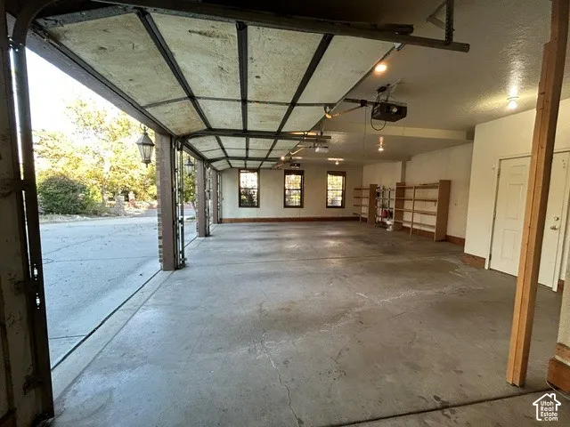 Multi-car garage featuring a concrete floor, built-in wooden shelving, multiple windows, and two separate entry doors