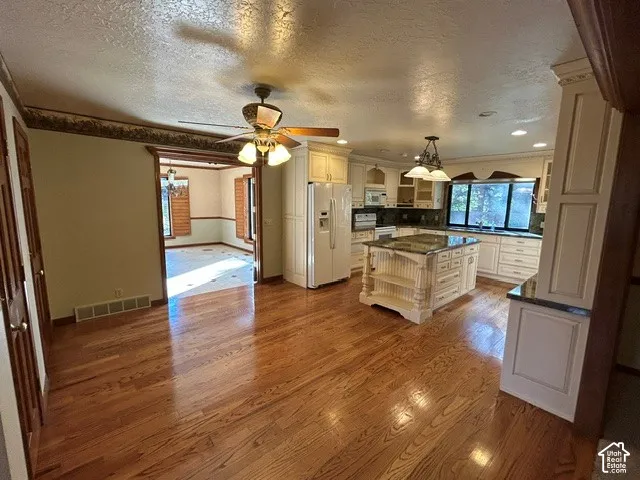Informal Dining featuring hardwood flooring, a center island with integrated shelving, stone countertops, custom cabinetry, and recessed lighting