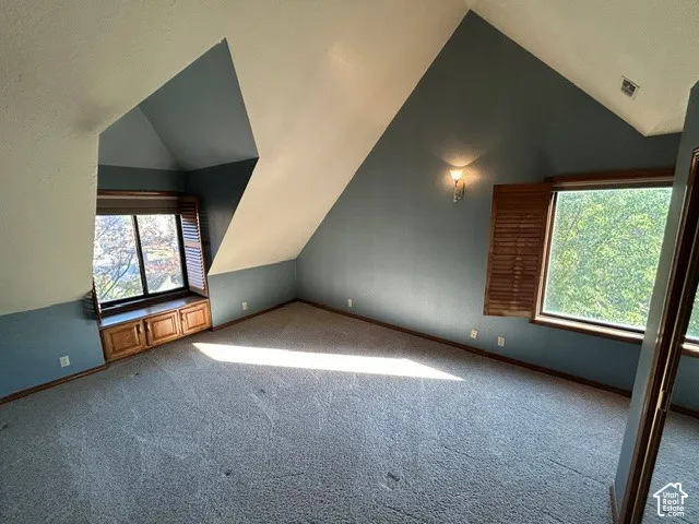 Upstairs Bedroom two - a Vaulted ceilings with architectural angles, built-in wooden cabinetry, dual windows with integrated shutters, and a wall-mounted light fixture