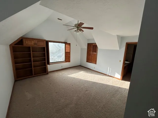 Upstairs Bedroom three - Vaulted ceilings featuring a central paddle fan, built-in wooden shelving, and shutter-style window treatments