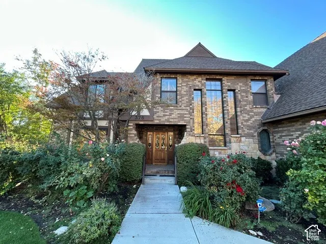 Multi-level masonry exterior featuring brick facade, gabled rooflines, decorative timber accents, multi-pane glass entry door, and vertical transom windows