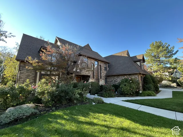 Multi-story residence featuring brick and masonry exterior, steeply pitched rooflines, and a concrete walkway