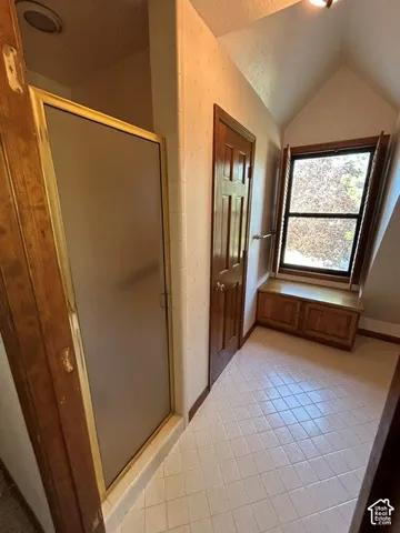 Upstairs Master Bathroom featuring a shower stall with a framed glass door, ceramic tile flooring, built-in cabinetry beneath a window, and wood-finish trim and doors