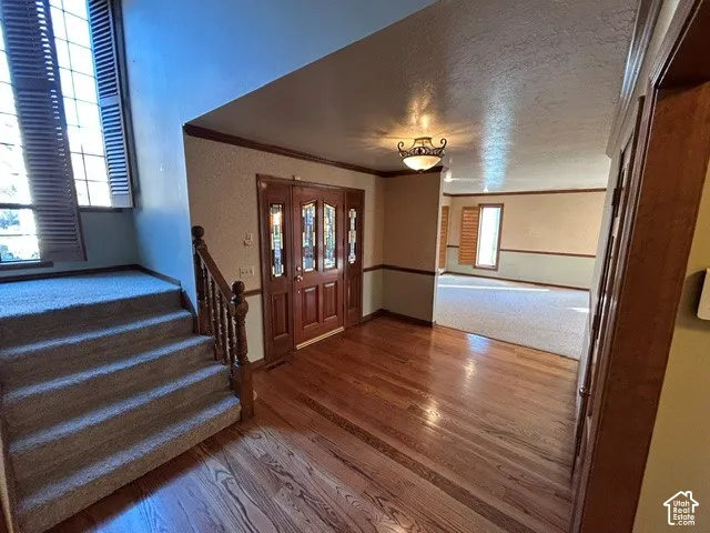 Entryway featuring wood flooring, a multi-pane wood door with decorative glass insets, a staircase with a wooden banister, and a semi-flush mount ceiling fixture