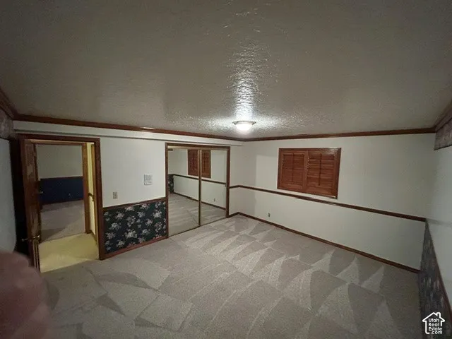 Downstairs Bedroom two featuring wood-finish chair rail molding, mirrored closet doors, and wood-shutter window coverings
