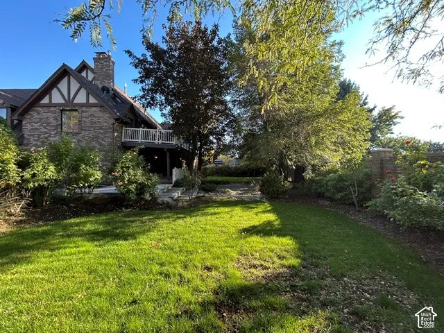 Backyard-Long view. Tudor-style exterior featuring stone masonry, half-timbered gables, elevated wood deck, stone patio, and perimeter privacy wall