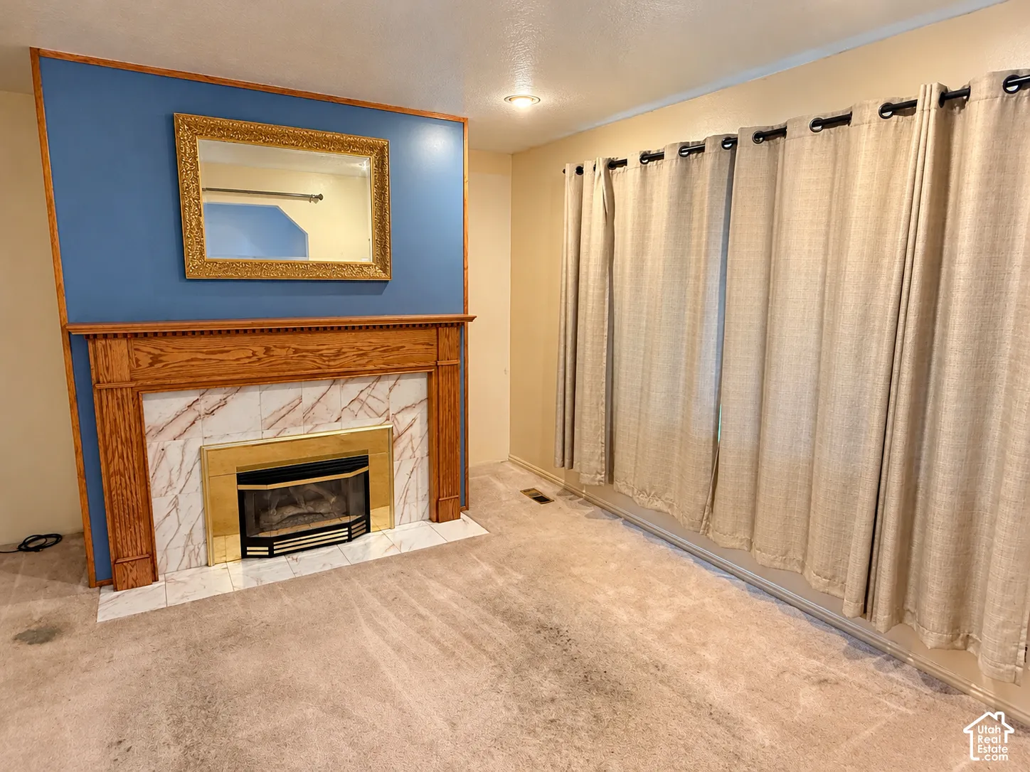 Fireplace featuring a wood mantel, stone-tile surround, and gold-finish metal firebox, accented by a bold blue wall and recessed ceiling lighting
