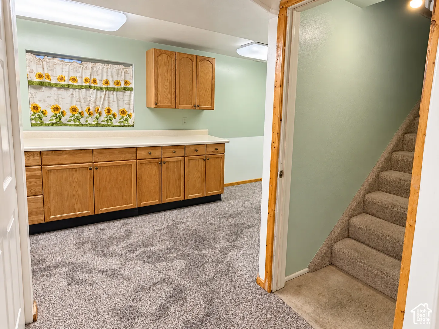 Wood-finish cabinetry with extensive counter space, solid-surface countertops, and carpeted flooring throughout
