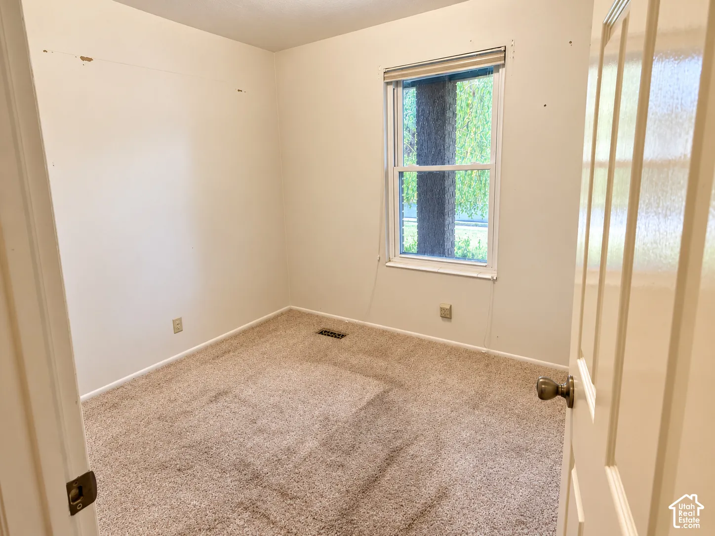 Neutral-toned carpeting, white walls, and a single-pane window with white trim